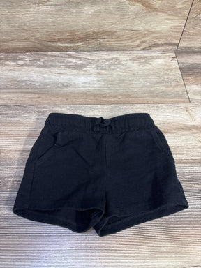 Flat lay front view of toddler black Cat & Jack knit shorts showcasing elastic waistband with tie and side pockets on a light wood floor
