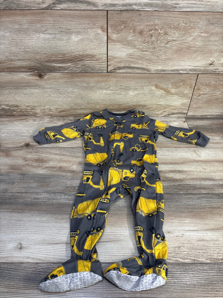 Flat lay of Just One You footed sleeper (size 18m) showcasing yellow construction vehicle print and front zipper on light wood floor