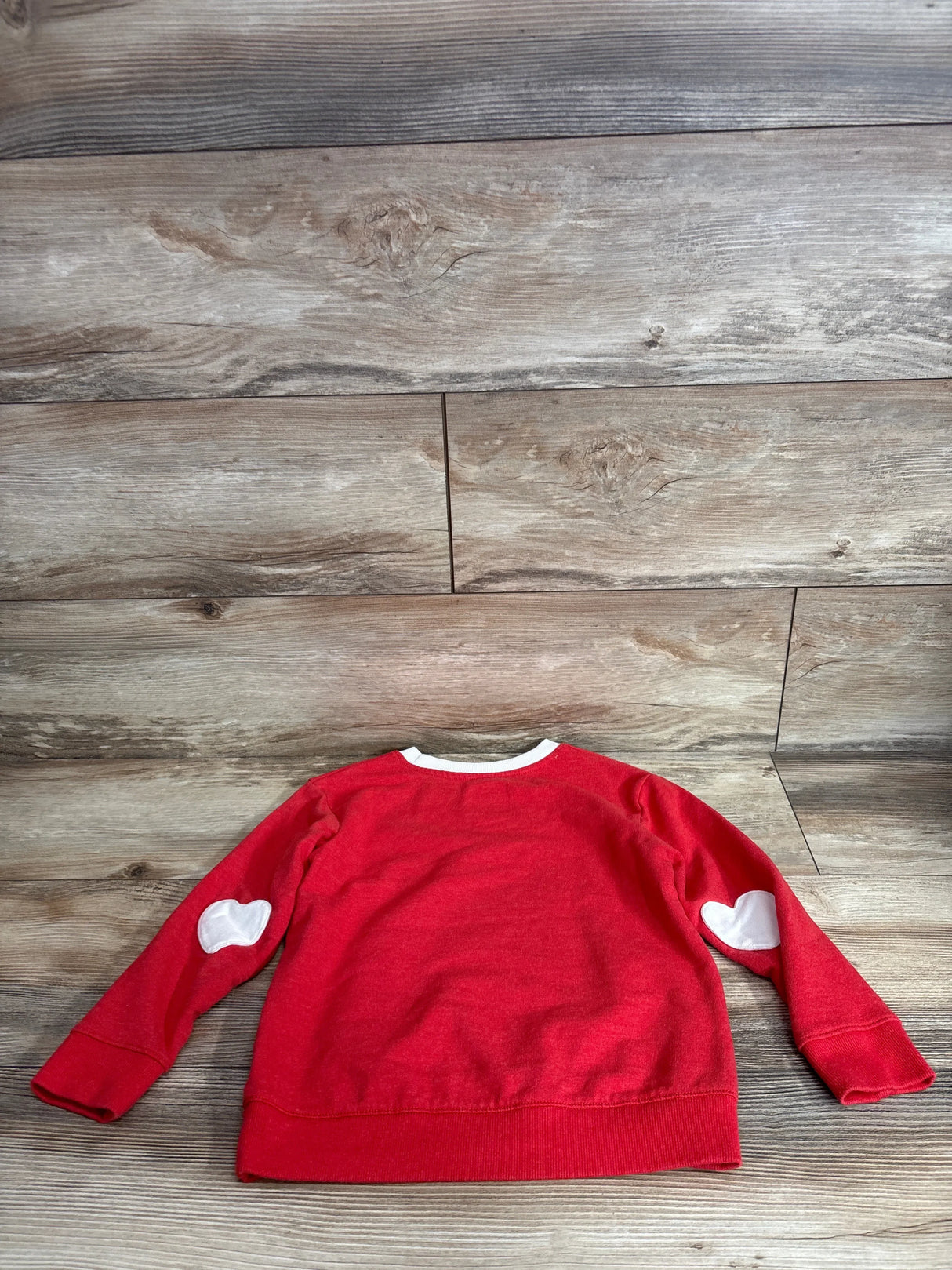 Back view of Cat and Jack red pullover sweatshirt 5T showing white heart elbow patches and white neckline trim on wood floor