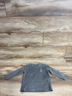 Front view of grey Volcom toddler long-sleeve shirt (2T) showing black-and-white diamond logo on chest and sleeve on wood floor background