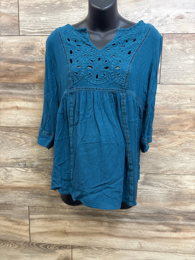 Front view of teal maternity lace top showing crochet lace yoke and ladder trim on black mannequin with wood background