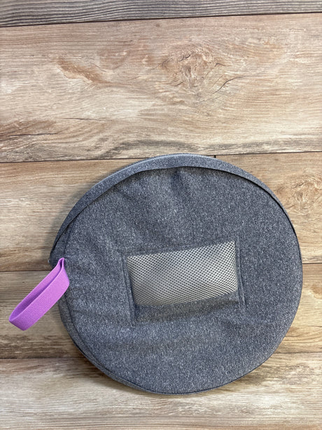Top-down view of Frida Mom donut perineal cushion in gray zip case showing mesh pocket and purple handle on wood floor