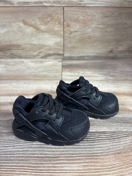 Three-quarter view of Nike Huarache Run TD Triple Black sneakers, size 4C, with mesh and leather panels on wood flooring