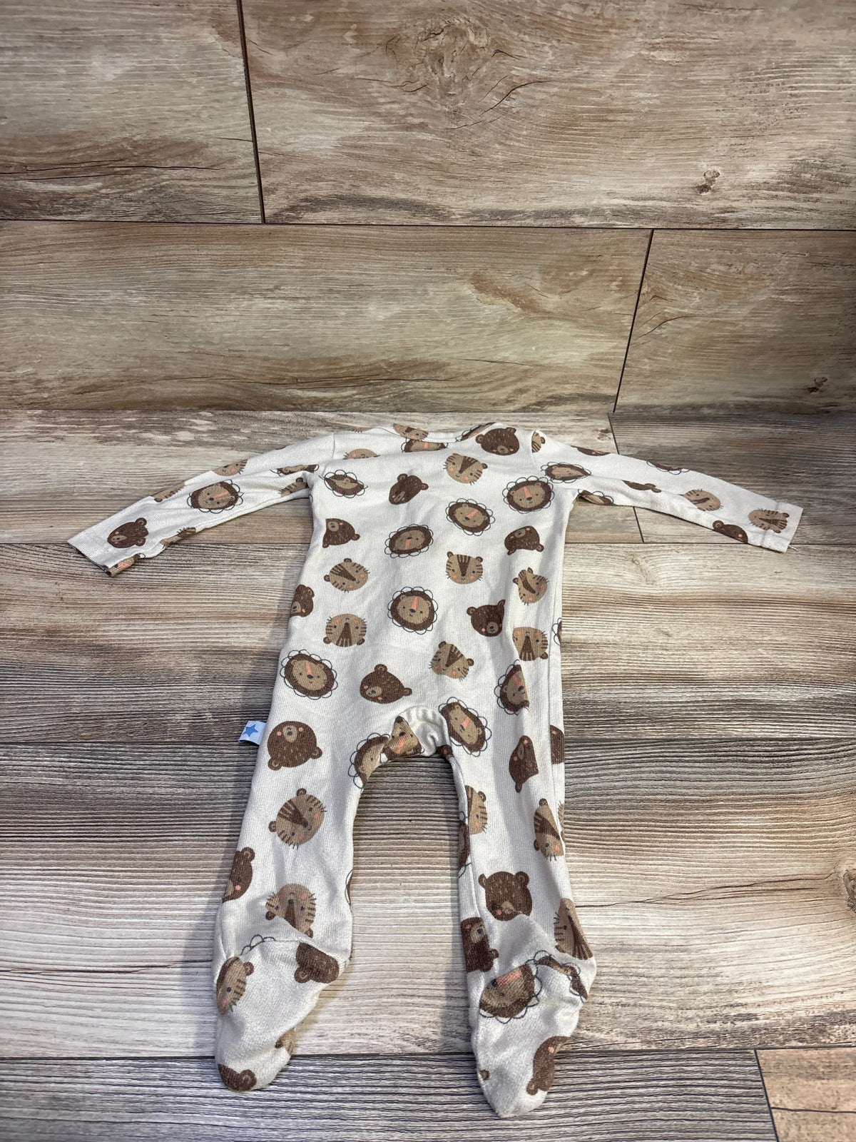 Top view of tan Millie and Myles sleeper showcasing long sleeves, footed legs, and animal print on a wood-look background