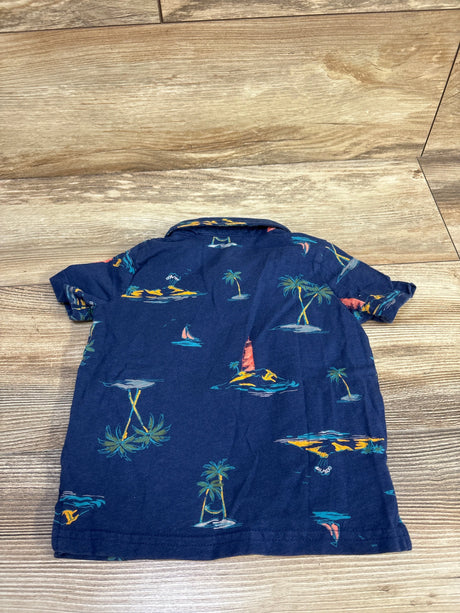 Back view of Carter's navy toddler polo shirt showcasing palm tree and island print and short sleeves with wood floor background