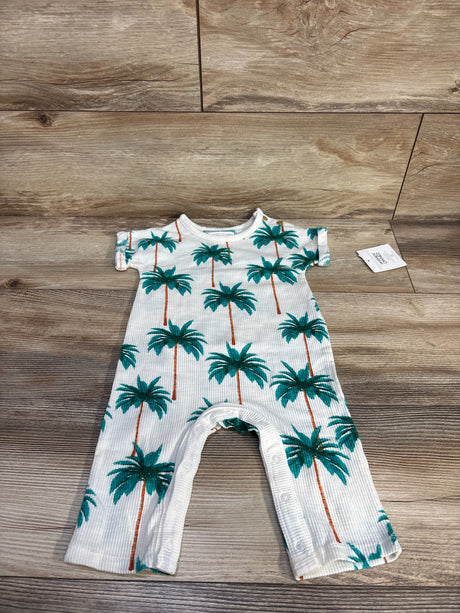 Front flat lay of white ribbed baby jumpsuit showcasing green palm tree print, short sleeves, and snap inseam on wood floor