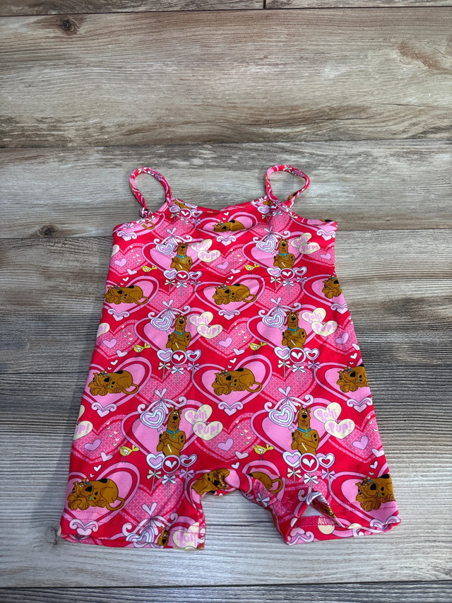 Flat lay of pink Shein x Scooby-Doo shortie romper showing spaghetti straps and all-over heart and Scooby-Doo print on wood plank background