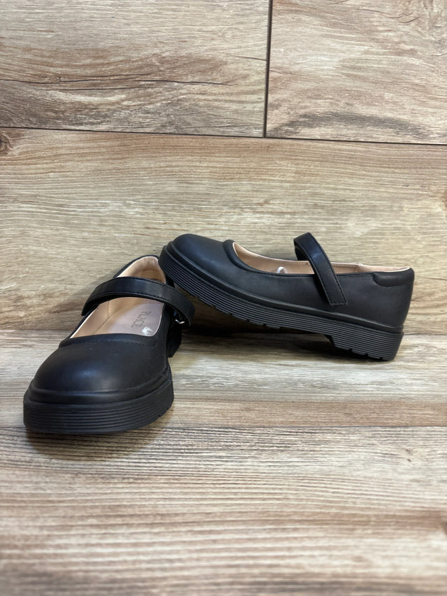 Black kids Mary Jane shoes with thick soles and Velcro strap on wood floor
