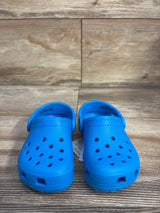 Front view of kids' Crocs Classic clogs size 7C showing ventilation holes and heel strap on wood floor background