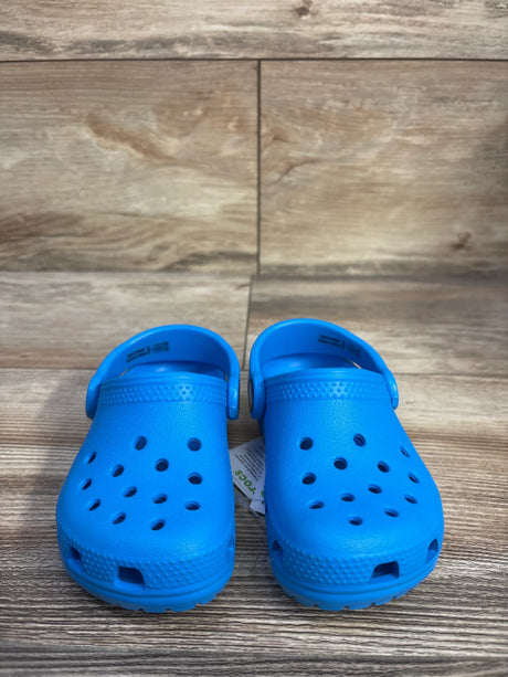 Front view of kids' Crocs Classic clogs size 7C showing ventilation holes and heel strap on wood floor background