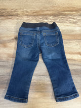 Back view of baby jeans with elastic waistband and back pockets laid flat on wood plank background