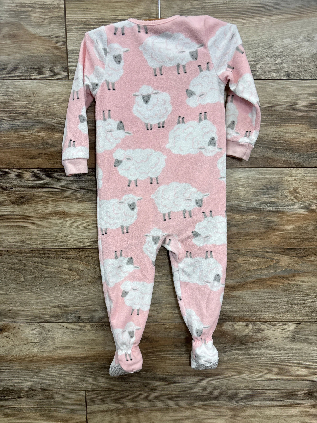 Pink footed baby sleeper with white sheep print on wood floor