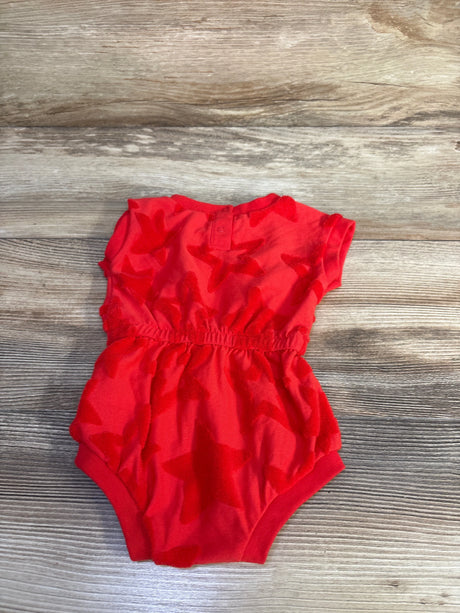 Top-down view of red Cat and Jack terry romper with elastic waist, cap sleeves, and raised star texture on wood background