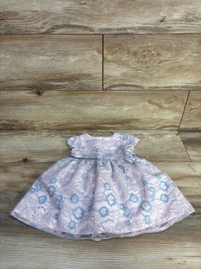 Pink baby dress with blue floral lace pattern on wooden floor