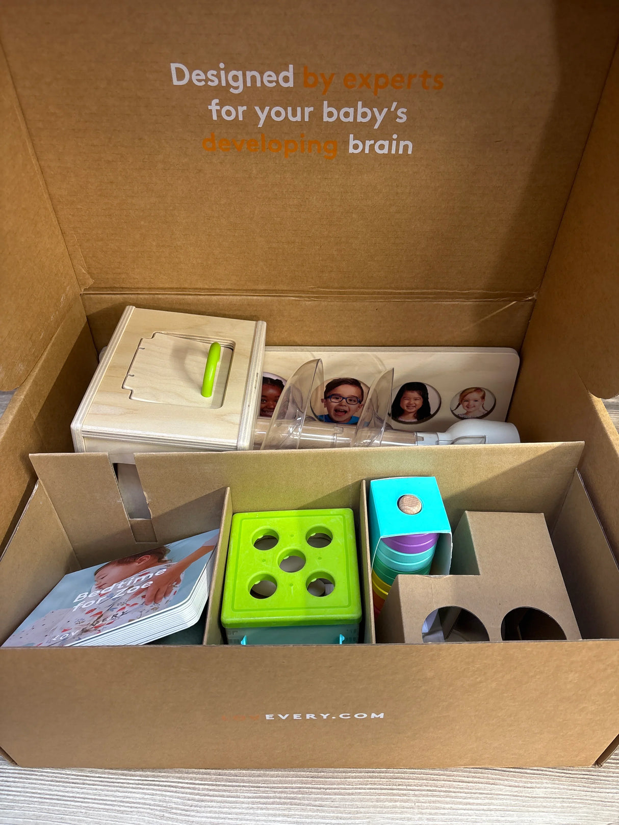 Top view of The Babbler Play Kit with shape sorter and cups; box reads Designed by experts for your baby's developing brain