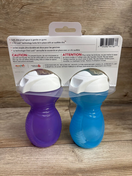 Front view of Munchkin Click Lock bite-proof sippy cups two-pack in purple and blue with white lids on wood