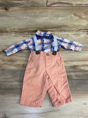 Baby boy outfit with pink pants, plaid shirt, suspenders, and blue bow tie on wood background