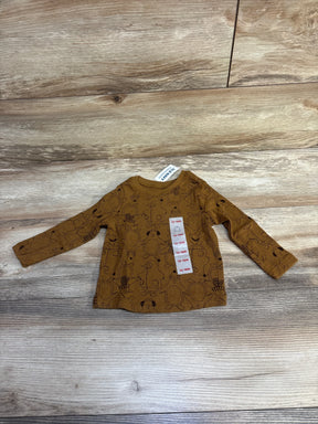 Brown long-sleeve toddler shirt with black animal illustrations and size tag 12-18M on wooden floor