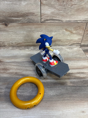 Sonic the Hedgehog toy figure on wheeled platform with yellow ring accessory, on wood background