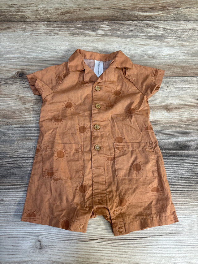 Rust-colored baby romper with sun pattern, short sleeves, and front buttons on wood background.
