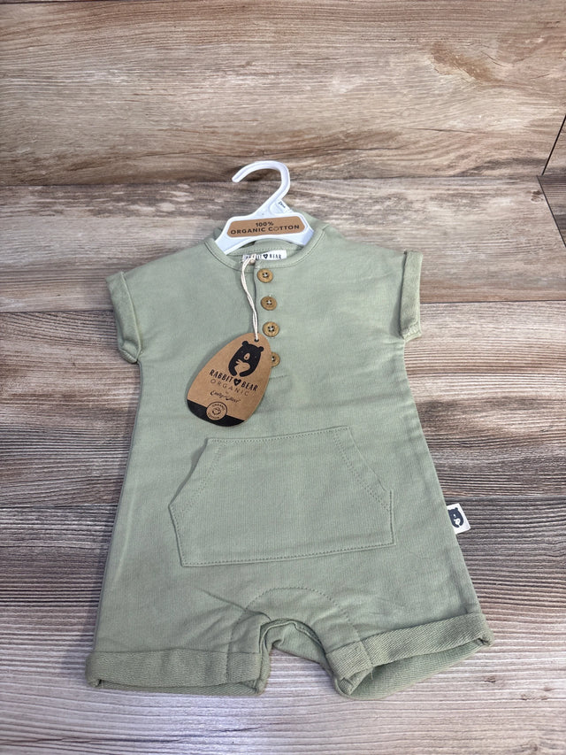 Front view of green Rabbit and Bear organic henley shortie romper showing three wooden buttons, kangaroo pocket, and brand tag on wood background