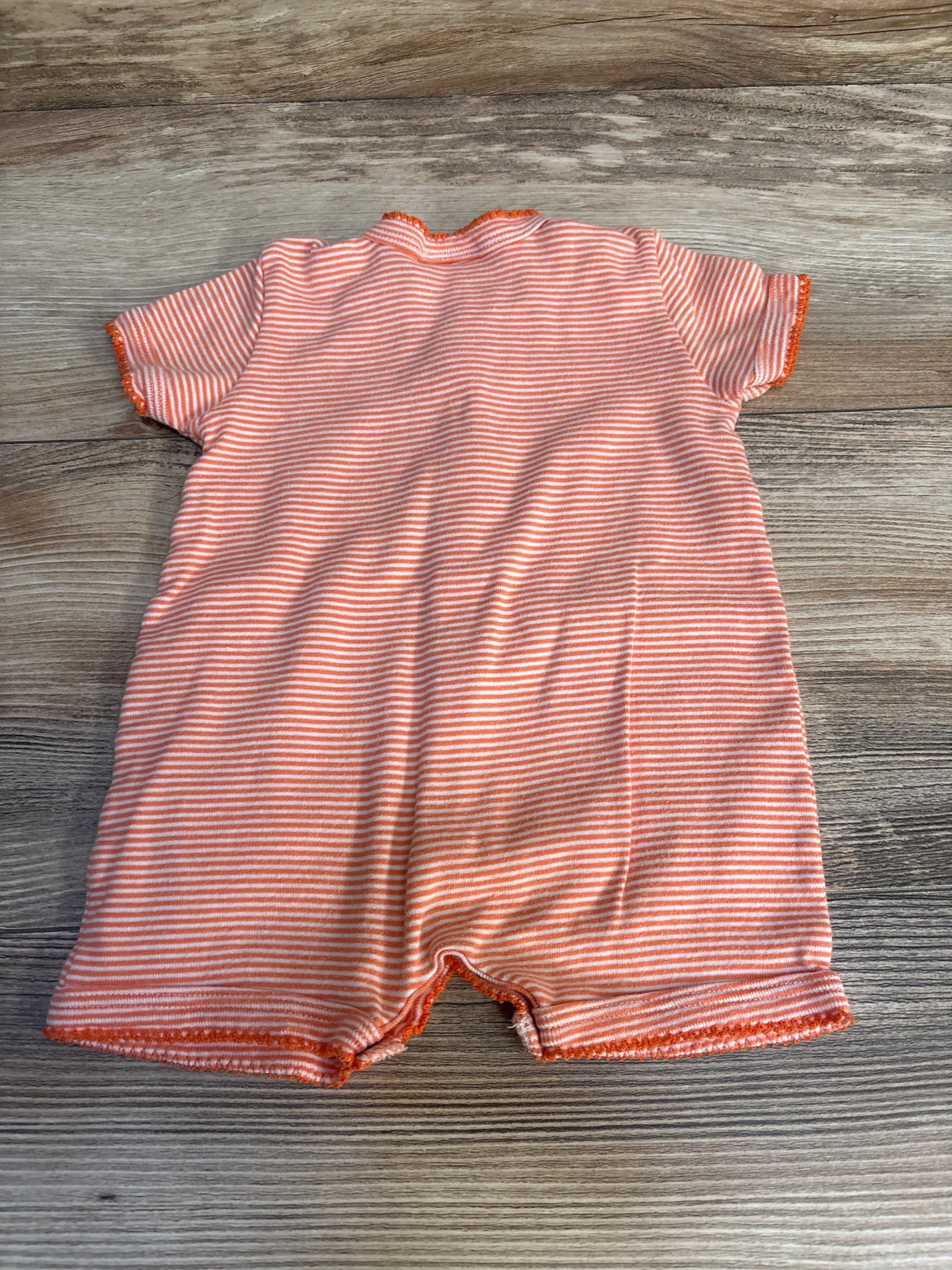Back view of Petite Bateau orange and white striped short sleeve shortie romper on wood plank floor