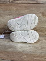 Pair of pink toddler shoes with white non-slip soles on wood background