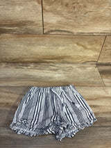 Top-down of white and navy striped pull-on baby shorts with elastic drawstring waist and ruffled hem on wood