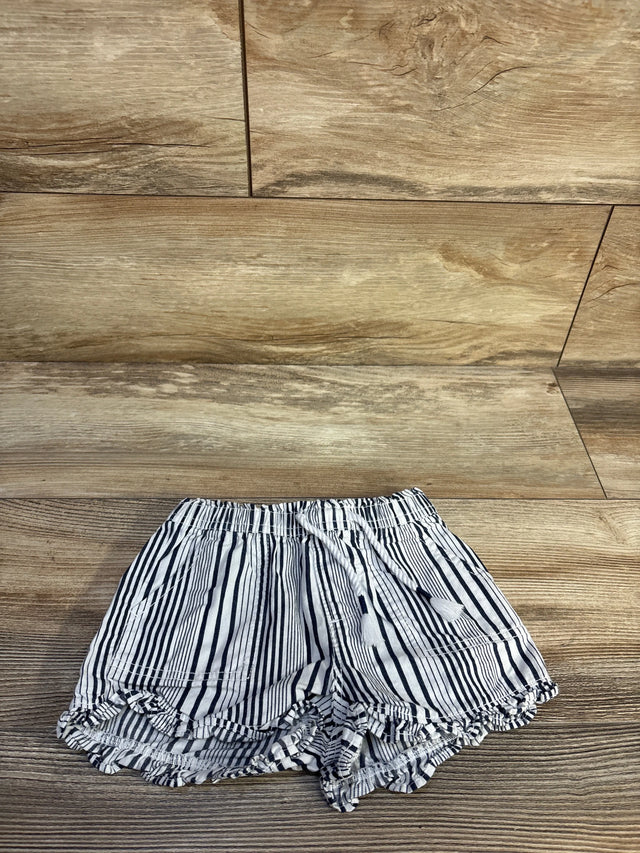Top-down of white and navy striped pull-on baby shorts with elastic drawstring waist and ruffled hem on wood
