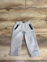 Light gray toddler sweatpants with black zippered pockets and elastic cuffs on wooden floor