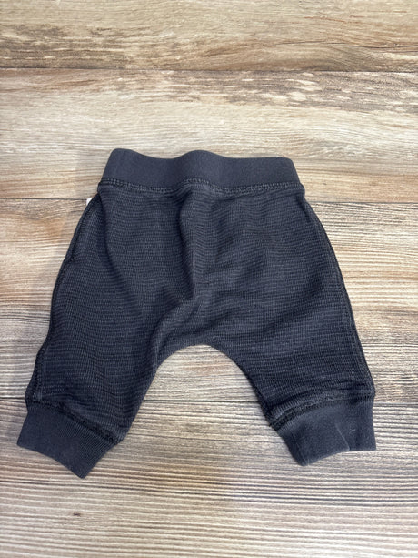 Black textured baby pants on wooden surface from children's resale store Me n Mommy To Be