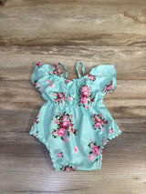 Flat lay of blue floral off-shoulder baby romper showcasing ruffled neckline, adjustable straps, elastic waist, and lace trim on wood background