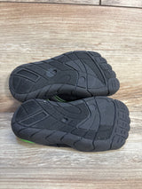 Black rubber soles of kids’ shoes with tread pattern on wood background