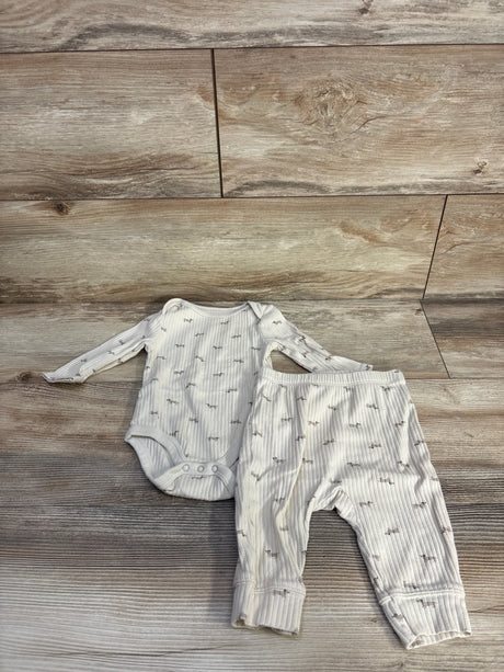 Flat lay of beige ribbed bodysuit and matching pants with ribbed texture and gray print on wood floor background