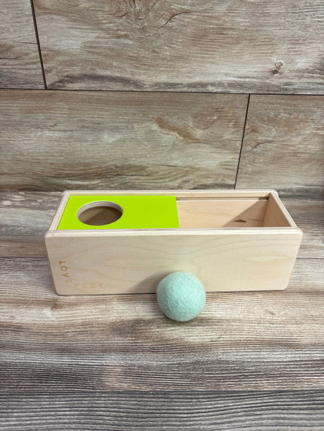Angled view of Lovevery Sliding Top Box showcasing its open sliding top and green panel with circular opening on a wood floor