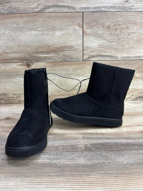Pair of black children's winter boots with ribbed soles on wooden floor background