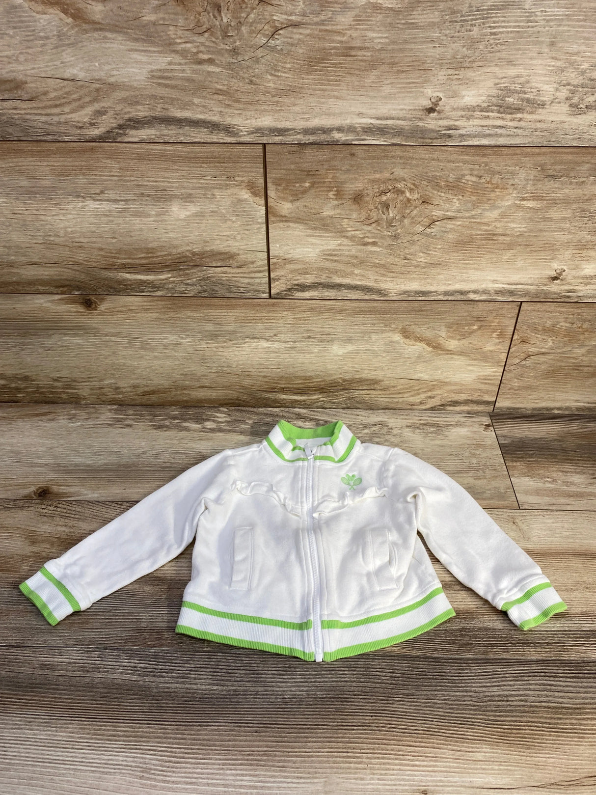Flat lay of Janie and Jack Disney Mickey Mouse ruffle tennis jacket sz 2T showcasing white zip-up with green trim and ruffle front on wood