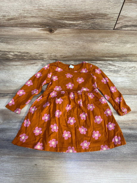 Long sleeve orange toddler dress with pink floral print, laid flat on wood background