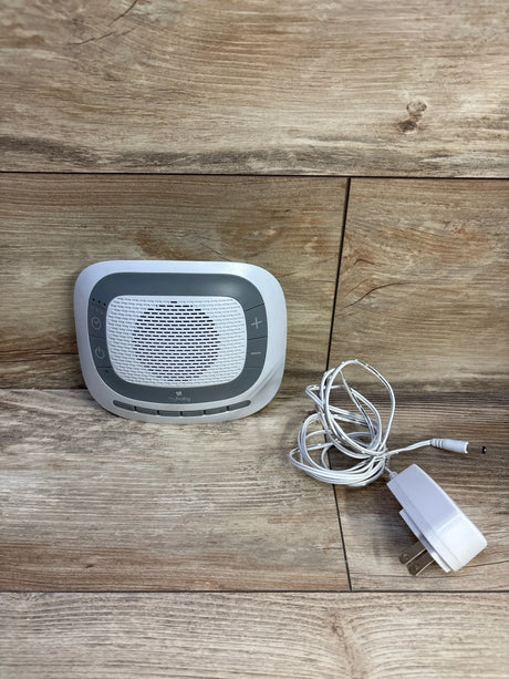 Front view of Homedics MyBaby SoundSpa portable sound machine showing speaker grille, control buttons, and included power adapter on wood background