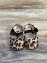 Front view of H&M baby leopard-print ballet flats showing black velvet bow straps on wood-grain background