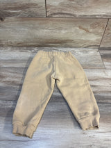 Back view of Champion beige toddler joggers showcasing elastic waistband and ribbed ankle cuffs on light wood background