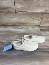 Side view of Cat & Jack Tyler toddler slip-on sneakers in off-white canvas with white rubber sole on wood background