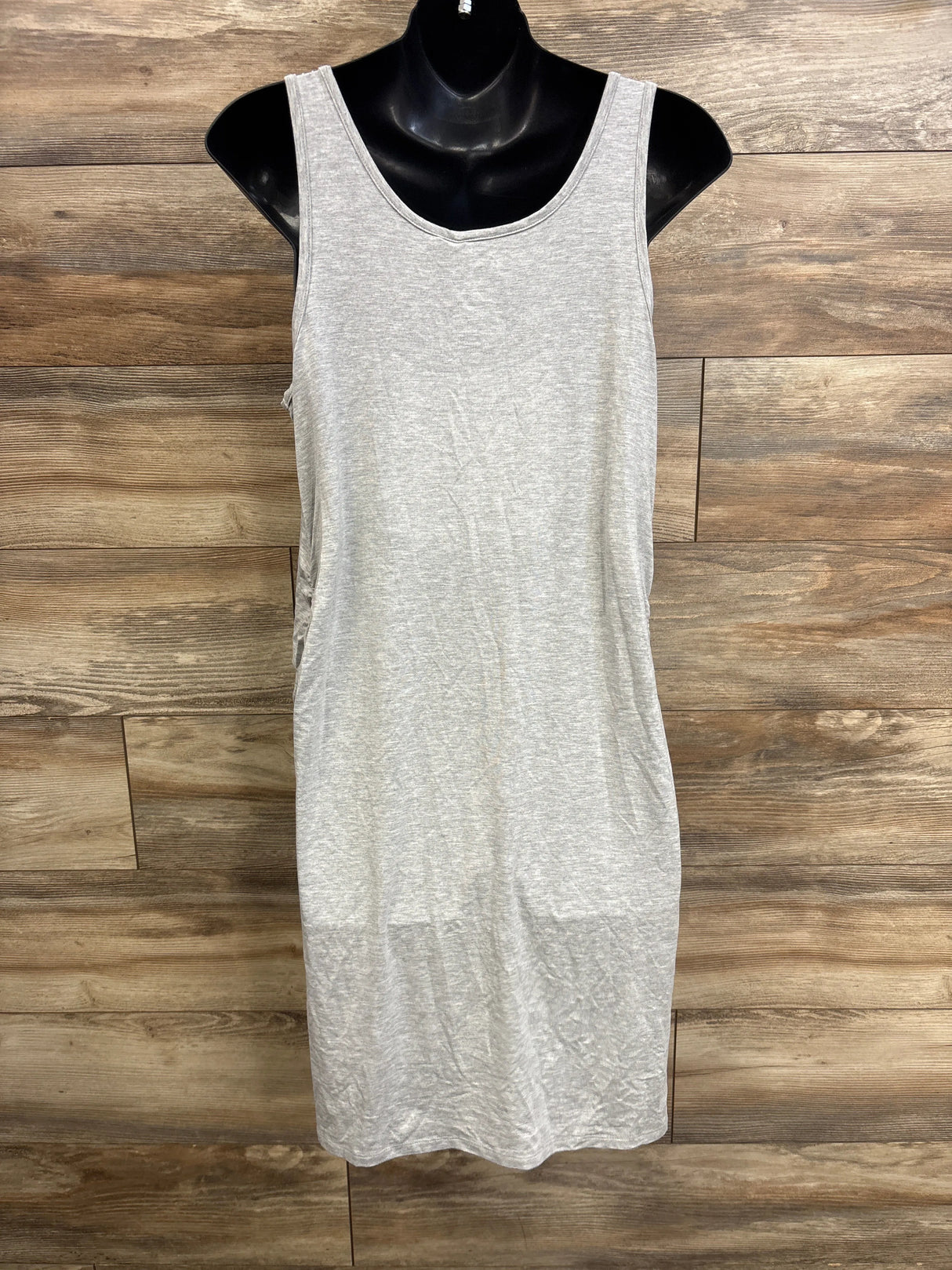Front view of grey maternity ruched tank dress with side ruching and scoop neckline on black mannequin against wood backdrop
