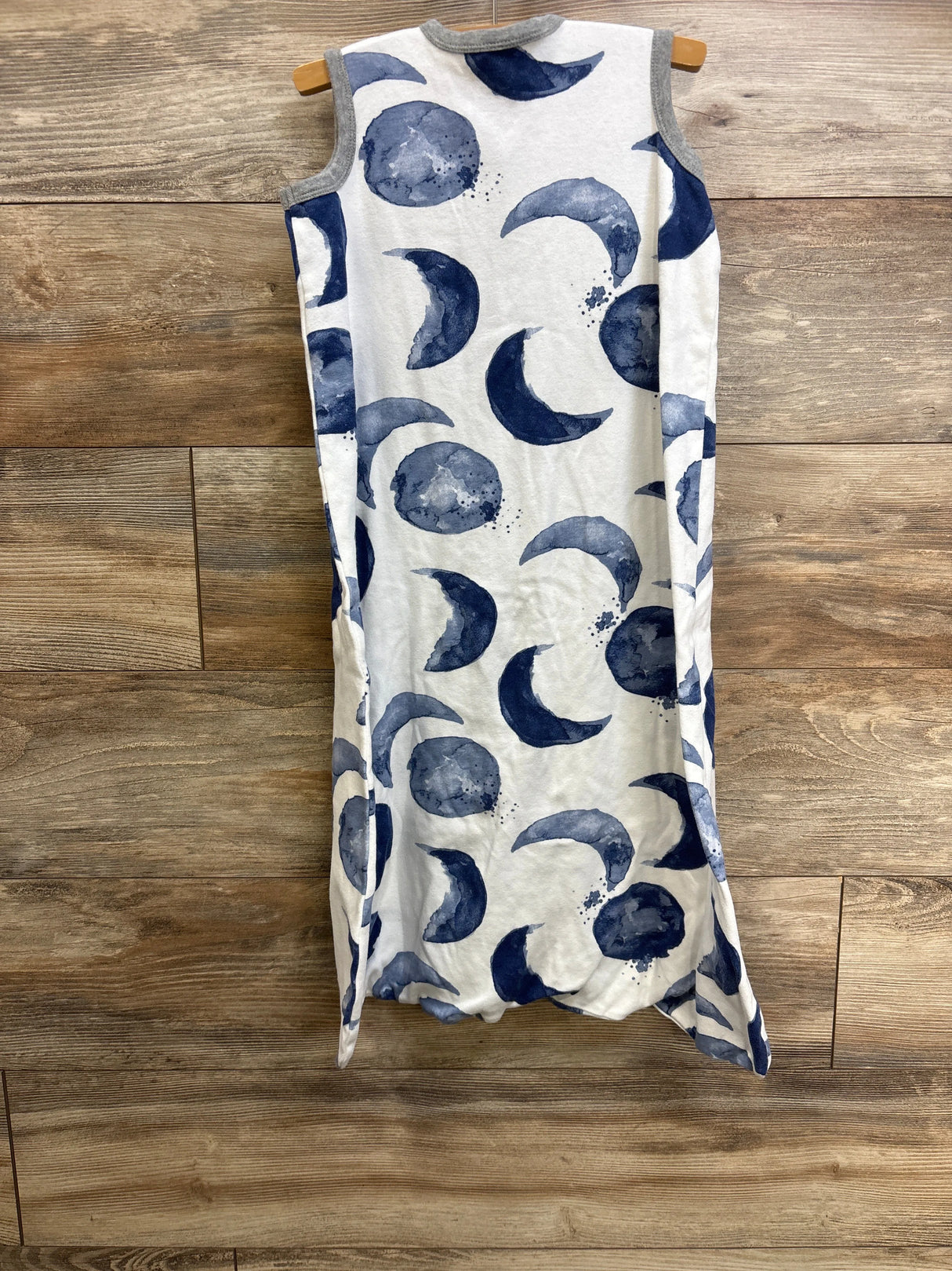 Hanging front view of Burt's Bees Baby beekeeper sleepsack showing navy watercolor moon print and gray trim on wood backdrop