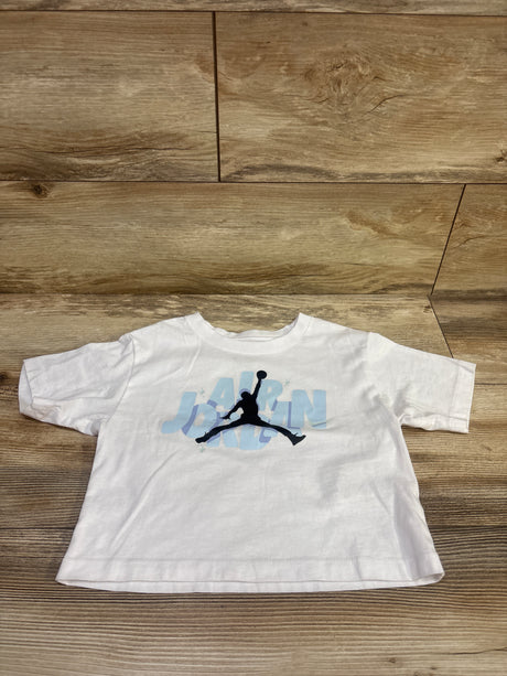 Front view of white Jordan shirt in size 5T showcasing a Jumpman graphic on a wood floor background