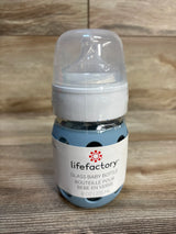 Lifefactory 8oz glass baby bottle with blue silicone sleeve on wood background