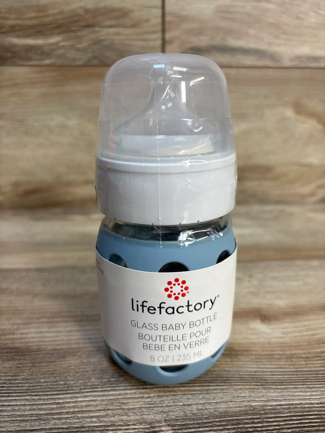 Lifefactory 8oz glass baby bottle with blue silicone sleeve on wood background