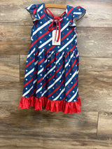 Front view of Pete & Lucy girls' Stars and Stripes dress showcasing diagonal red and white star-and-stripe print, flutter sleeves, red tie neckline and red ruffle hem on wood background