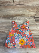Top-down of Carter's girls' blue floral tank top size 2T with ruffled straps and multicolor flower print on wood background