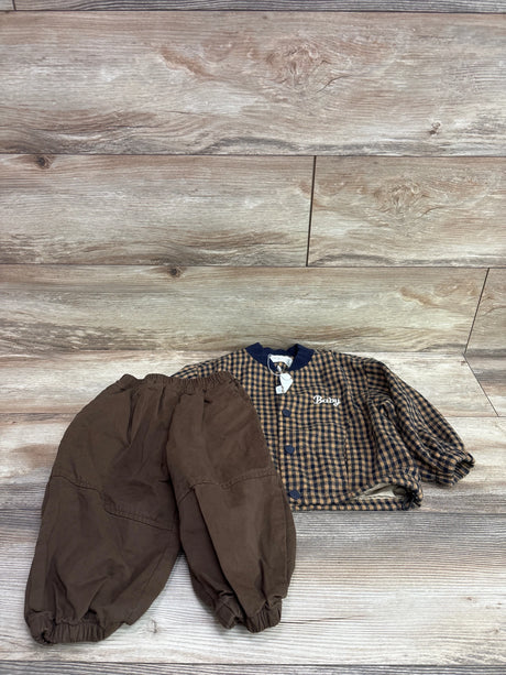 Top-down view of Tobbie’s Closet brown 2-piece flannel top and pants set in size 2T, showing plaid button-up top and elastic cuffs on wood